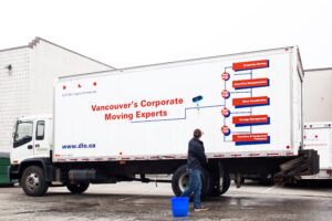 Moving Truck with "Vancouvers Corporate Moving Experts" written on the side being washed by a man