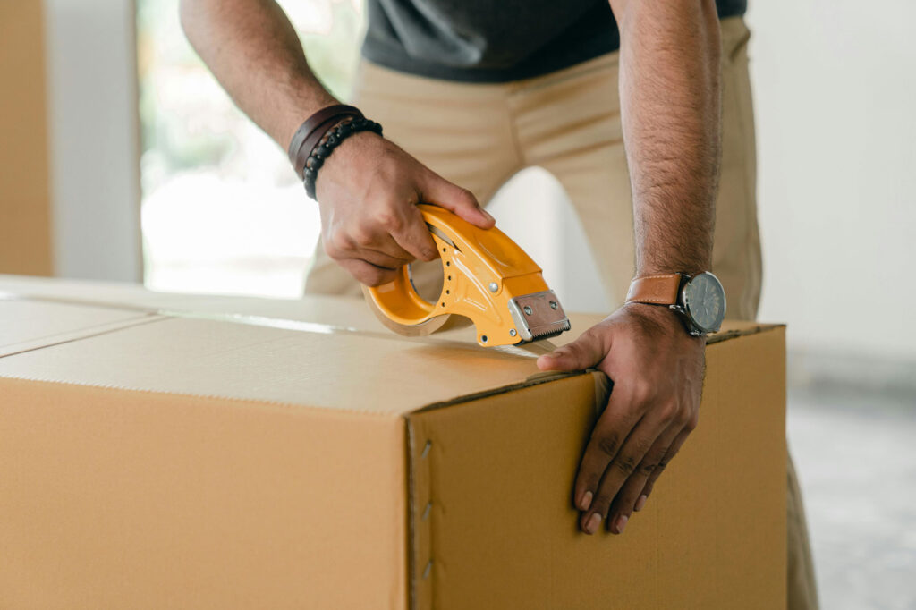 Person taping a cardboard box to prep for moving